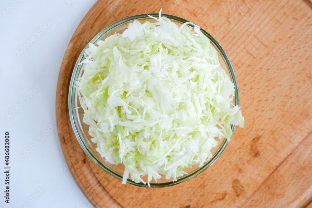 Shredded white cabbage on a wooden board. Fermentation of vegetables. Healthy food. Superfood and health care. Immune system support. Alternative medicine. Dietary supplement. Shredded white cabbage on a wooden board. Fermentation of vegetables. Healthy food. Superfood and health care. Immune system support. Alternative medicine. Dietary supplement.
