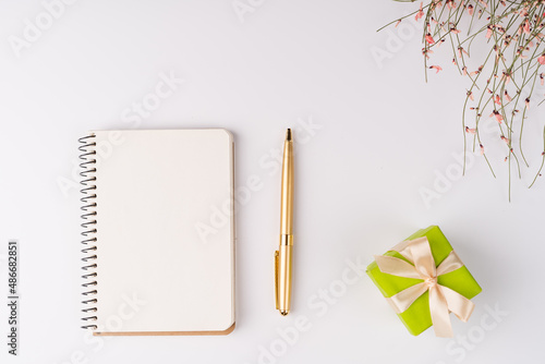 Flat lay  top view  white background  small gift boxes and a bush of dried flowers with pink cute flowers for March 8  spring mood  notepad and pen