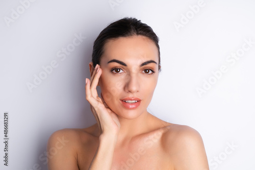 Close beauty portrait of a topless woman with perfect skin and natural make-up, plump nude lips, on a white background.