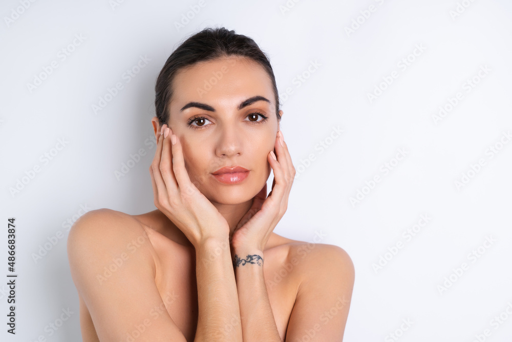 Close beauty portrait of a topless woman with perfect skin and natural make-up, plump nude lips, on a white background. Close beauty portrait of a topless woman with perfect skin and natural make-up, plump nude lips, on a white background.