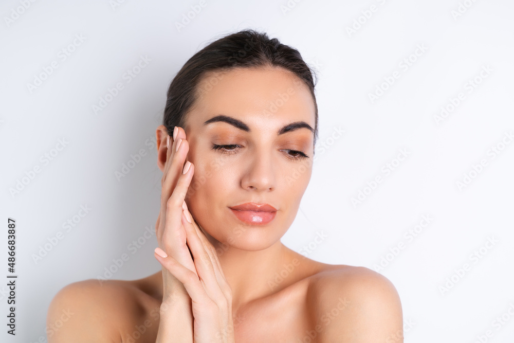 Close beauty portrait of a topless woman with perfect skin and natural make-up, plump nude lips, on a white background. Close beauty portrait of a topless woman with perfect skin and natural make-up, plump nude lips, on a white background.