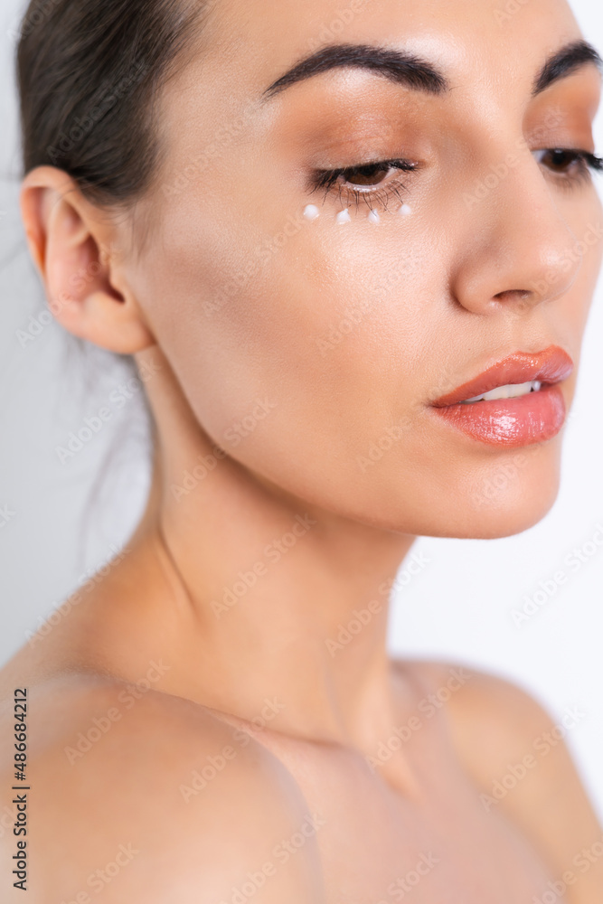 Close-up beauty portrait of a topless woman with perfect skin and natural make-up, with anti-aging cream dots to moisturize and firm the skin under the eyes. Close-up beauty portrait of a topless woman with perfect skin and natural make-up, with anti-aging cream dots to moisturize and firm the skin under the eyes.