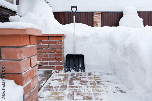 Big snow shovel is next to snowdrifts. Soft focus.Сoncept of cleaning a large amount of snow from sideway.