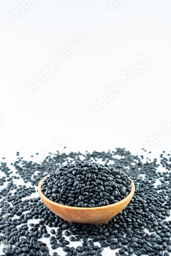 A bowl of small black beans on a white background