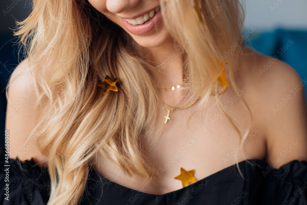 Portrait of young blond woman breast smiling and laughing. Decoration with gold paper and foil stars like confetti. 