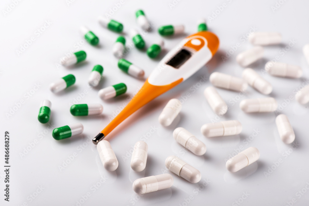 Electronic thermometer and pills on white background Electronic thermometer and pills on white background