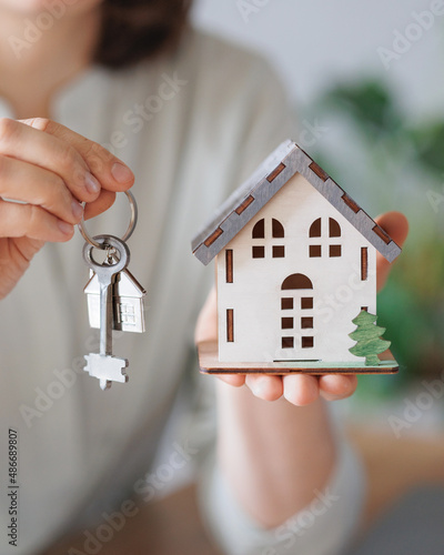 a woman realtor or mortgage agent holds a miniature of the house and keys in her hands. sale and purchase of real estate apartments or houses with a garden. conclusion of a dogvor for the rental of