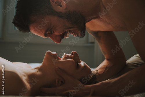 young couple relaxing in bed and having fun. Man and woman kissing and share love mood together. Concept about sex and lifestyle relationship