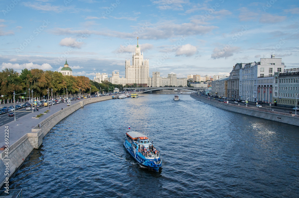 Naklejka premium Moscow in summer. View from Moskvoretskaya embankment to the high-rise on Kotelnicheskaya embankment. Pleasure boat on the Moscow River.