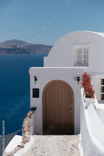 Beautiful brown door on white facade of greek architecture hotel in Oia city, Santorini island, Greece, Europe. Beautiful details of the island of Santorini. Famous travel destination with sea view