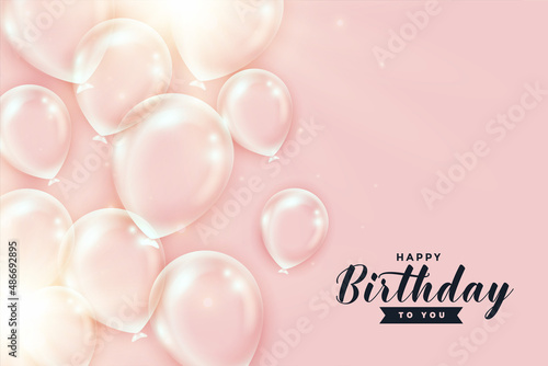 shiny transparent birthday balloons on peach color background