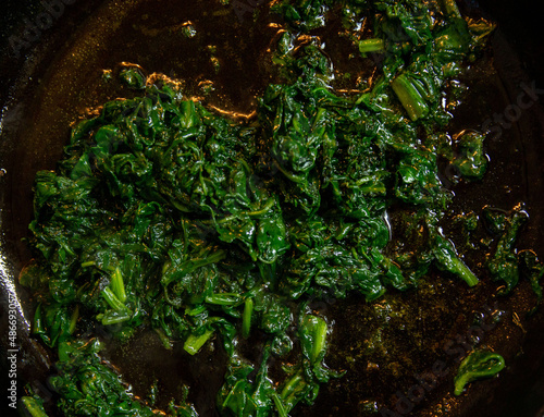 Fresh green spinach fried in a pan in oil. Cooking a vegetable dish. Flat lay