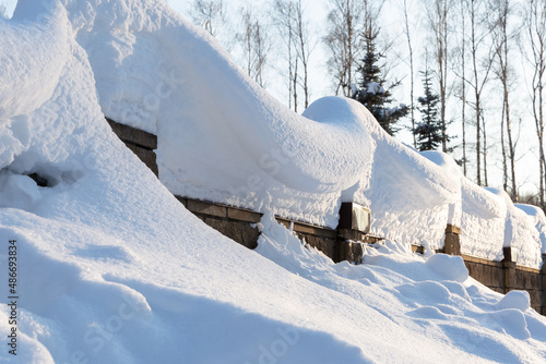 Overhanging beautifully curved snow caps on a fence in sunlight.Soft focus. Snowy winter concept.