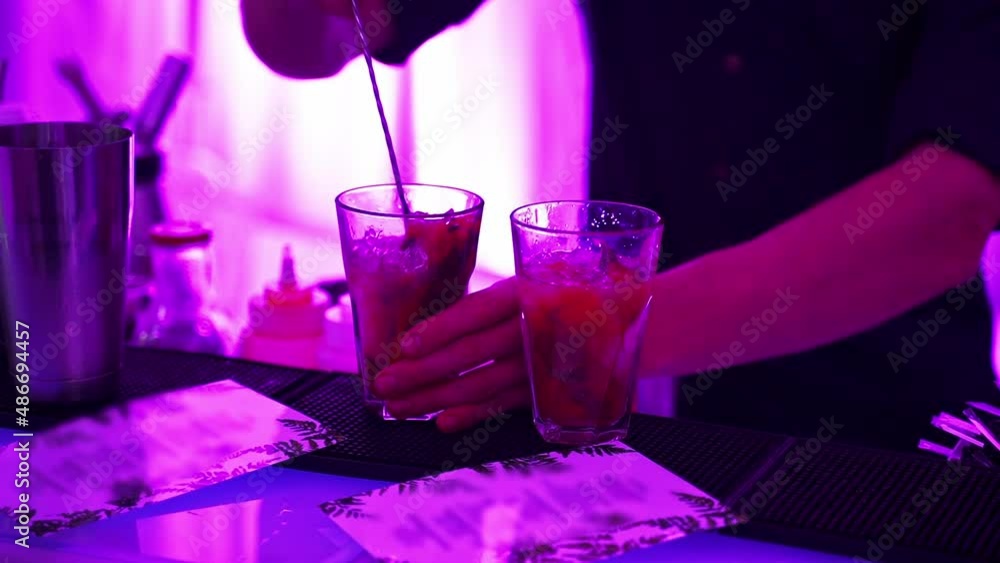 closeup of a bartender's hand stirs with a longhandled spoon in a