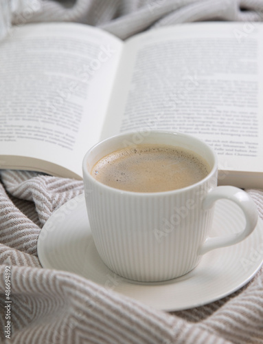 a cup of and a book on a cream blanket 