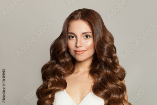 Beautiful female model with long and shiny wavy hair . Beauty woman with curly hairstyle . Fashion, cosmetics and makeup
