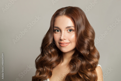 Portrait of young beautiful brunette model with natural makeup, trendy wavy hairdo and perfect skin.