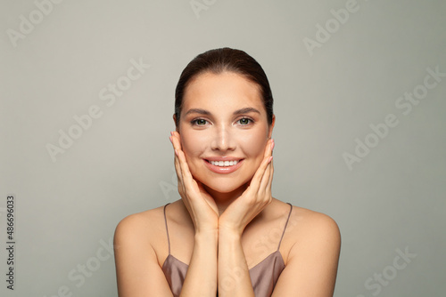Happy beautiful woman holding her cheeks her hands. Pretty spa model with clean fresh skin. Cosmetology, Beauty and Spa
