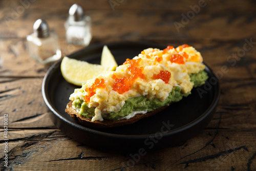 Healthy avocado toast with scrambled eggs and caviar