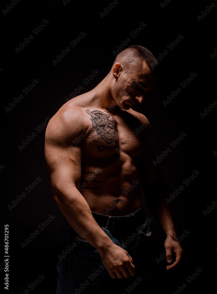 Fototapeta premium Man posing and showing his arm muscles while posing on black background