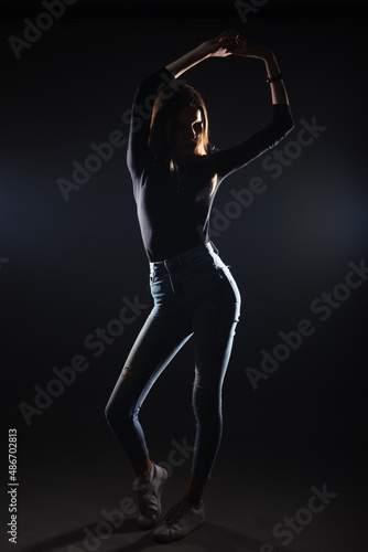 Silhouette picture of a young gorgeous woman posing on black background