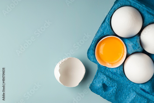 Fototapeta White chicken eggs in eco-packaging on a blue background
