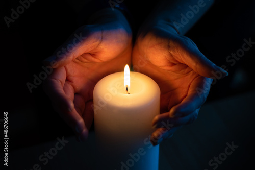 Hands warming at candle flame
