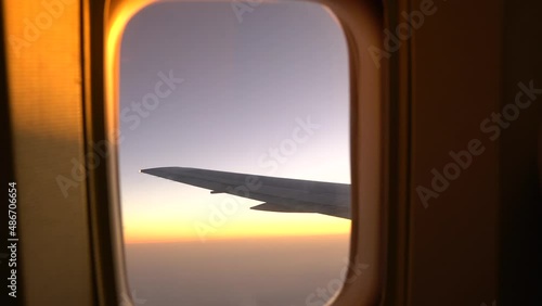 The hand opens the shutter of the aircraft porthole with a view of the wing of the aircraft and the clouds. View from airplane window. Window to a new life. Immigration or tourism visualization.