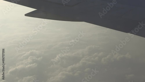 A beautiful view from the airplane window to the white clouds illuminated by the morning sun. Opening of borders and return of tourism. Airplane wing in the clouds.