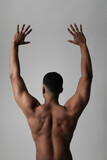 Strong athletic black man shows naked muscular body. Back view. Vertical.