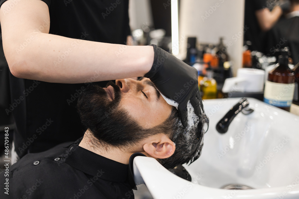 Hairdresser washes client head in barbershop Hairdresser washes client head in barbershop