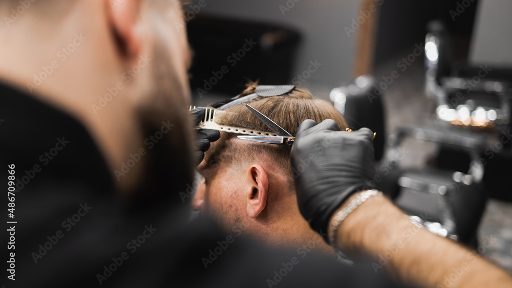 Hairdresser scissors hair on the head sides for a stylish black-haired man in the barbershop Hairdresser scissors hair on the head sides for a stylish black-haired man in the barbershop