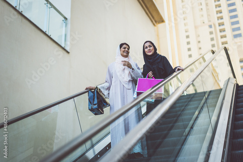 Two arabian girls spending time together outdoor making activities. Young women making shopping in Dubai