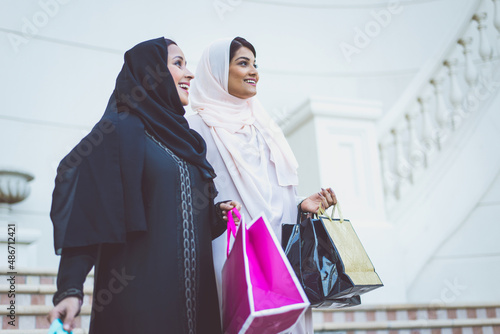 Two arabian girls spending time together outdoor making activities. Young women making shopping in Dubai