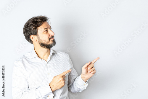 Businessman on gray background points to the side.