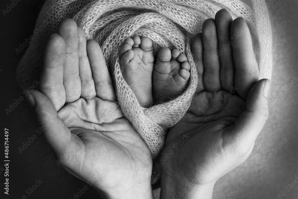 The palms of the father, the mother are holding the foot of the newborn