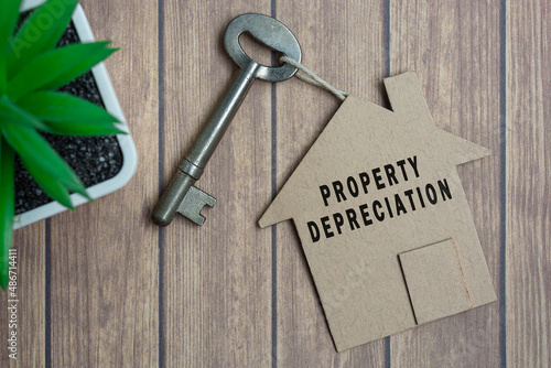 Fotografie Property depreciation text on house model and key on wooden desk