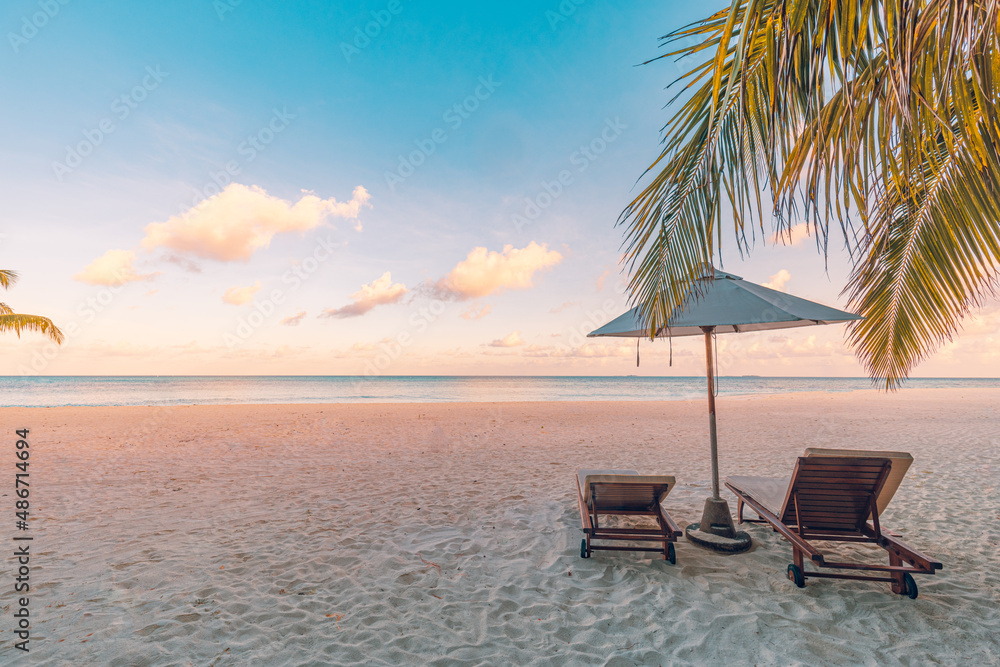 Panoramic tropical sunset scenery, two sun beds, loungers, umbrella under palm tree. White sand, sea horizon view colorful sunrise sunset sky calm relax mood. Summer couple vacation beach resort hotel