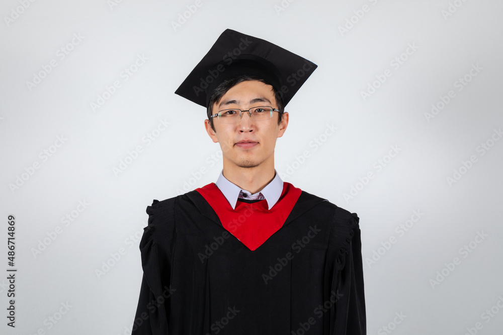 Graduate in glasses wearing gown and mortarboard on white background Graduate in glasses wearing gown and mortarboard on white background