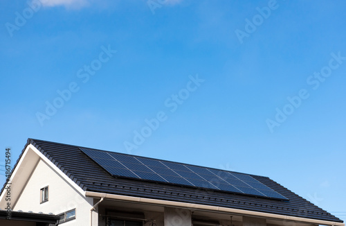 太陽光発電。太陽光パネルが設置された住宅の屋根と快晴の青空。