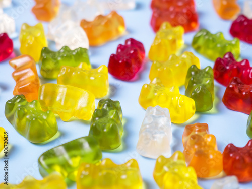 Delicious bright gummy bears on a blue background, flat lay