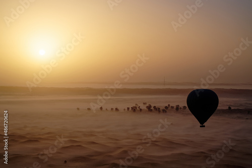 Canvas Print Silhouette of Tourist Hot Air Balloon flying over Dubai Desert during sunrise wi