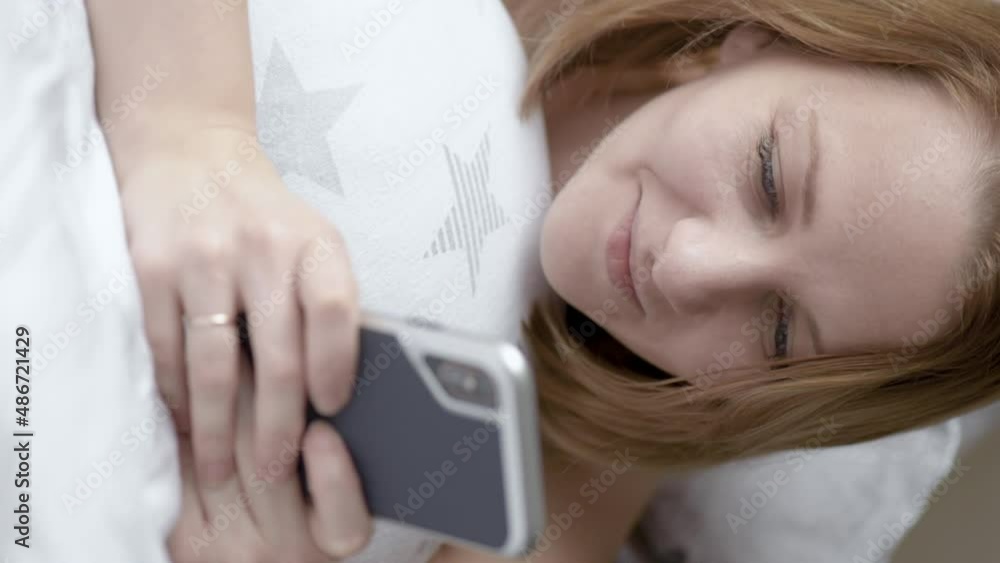 Vertical view beautiful woman are using smart phone on the bed in morning. Female surfing net with cellphone at home. Girl communicate with a friend on her mobile phone. Vertical view beautiful woman are using smart phone on the bed in morning. Female surfing net with cellphone at home. Girl communicate with a friend on her mobile phone.