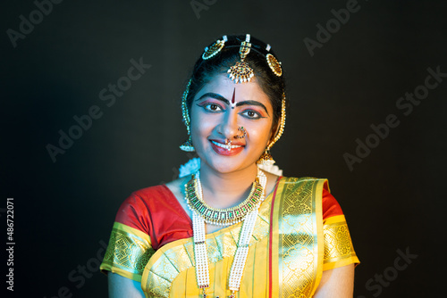 Portrait shot happy smiling Indian Bharatnatyam dancer on stage looking at camera - concept of classical dance, confident and traditional artist. photo