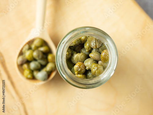 Capers in a glass jar. Pickled capers in a jar on a wooden board top view photo