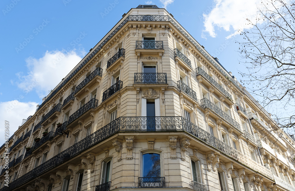 The flower-decked facade of traditional French house with typical balconies and windows. Paris.