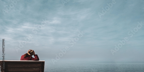 Fototapeta Unhappy single woman sitting on bench, looking at distant sea or seascape horizon