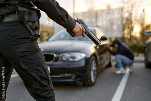 Policewoman holding gun at car thief backview