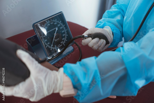 Tableau sur toile A nurse in full PPE gear Inflating a cuff to check the blood pressure