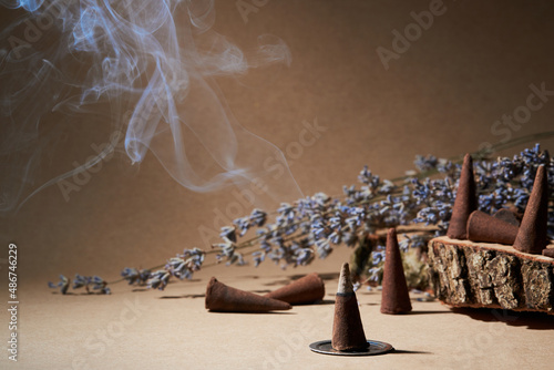 Incense cones for aromatherapy with lavender flowers on a brown background. Burning incense cone 